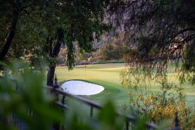 view of home's community featuring view of golf course and a lawn