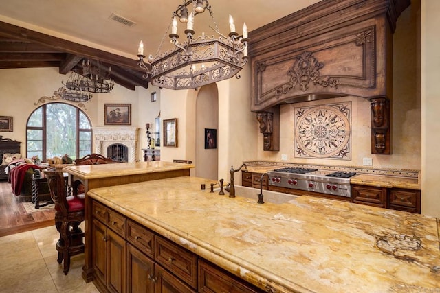 kitchen featuring arched walkways, a fireplace, visible vents, stainless steel gas stovetop, and open floor plan