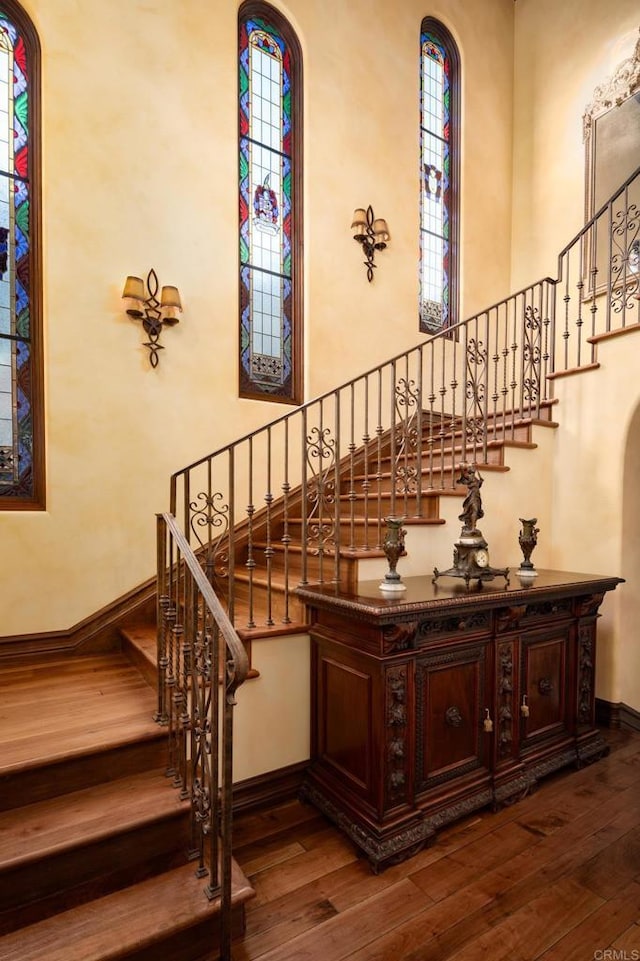 stairs with a high ceiling, hardwood / wood-style flooring, and baseboards