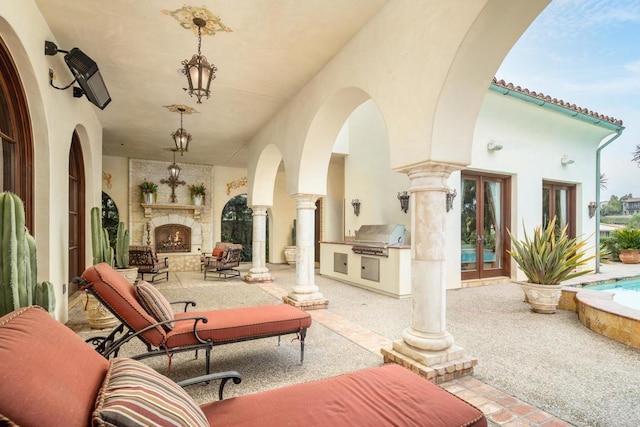 view of patio with an outdoor kitchen, french doors, an outdoor stone fireplace, and grilling area