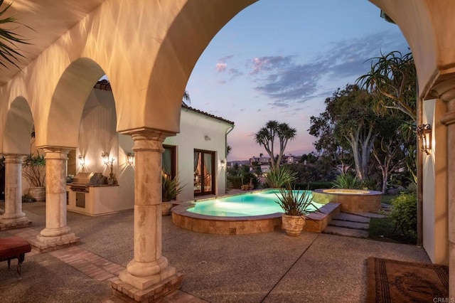 view of swimming pool with exterior kitchen, a patio, grilling area, and an in ground hot tub