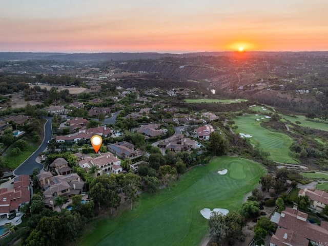 aerial view at dusk with view of golf course and a residential view