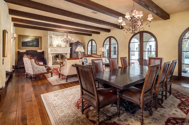 dining space featuring arched walkways, an inviting chandelier, a lit fireplace, french doors, and a healthy amount of sunlight