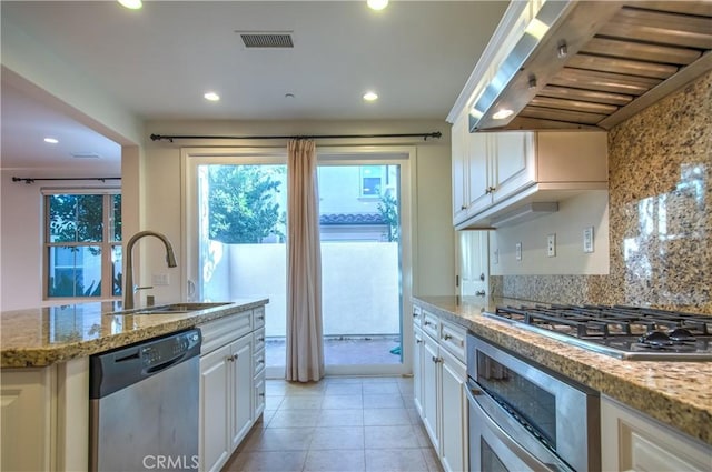 kitchen with visible vents, white cabinets, appliances with stainless steel finishes, extractor fan, and a sink