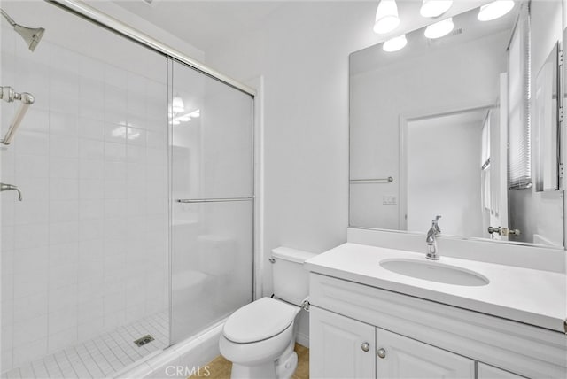 bathroom featuring a shower stall, toilet, and vanity