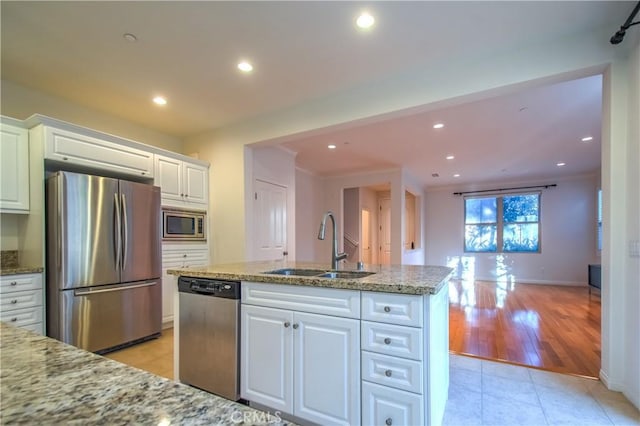 kitchen featuring light tile patterned floors, appliances with stainless steel finishes, light stone counters, white cabinetry, and a sink