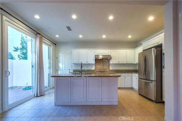 kitchen with a kitchen island with sink, under cabinet range hood, a sink, white cabinetry, and appliances with stainless steel finishes