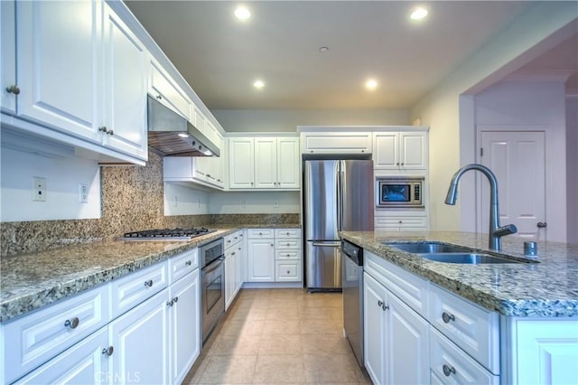 kitchen with recessed lighting, a sink, white cabinets, wall chimney range hood, and appliances with stainless steel finishes