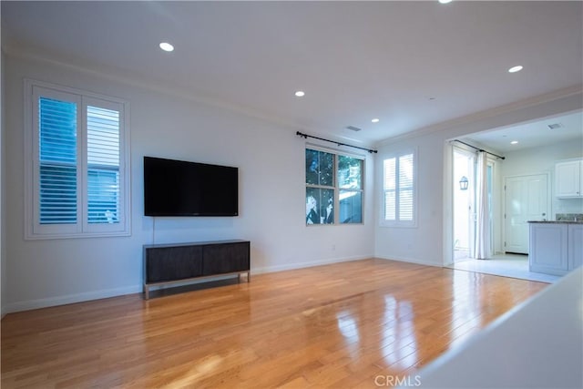 unfurnished living room with light wood-type flooring, baseboards, and recessed lighting