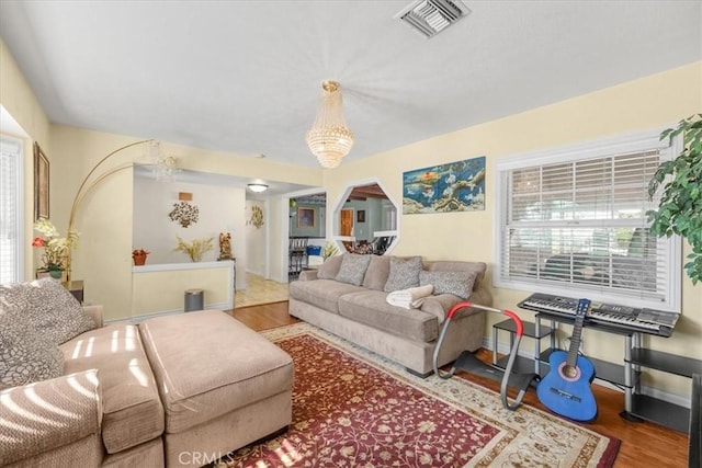 living room with baseboards, visible vents, arched walkways, and wood finished floors