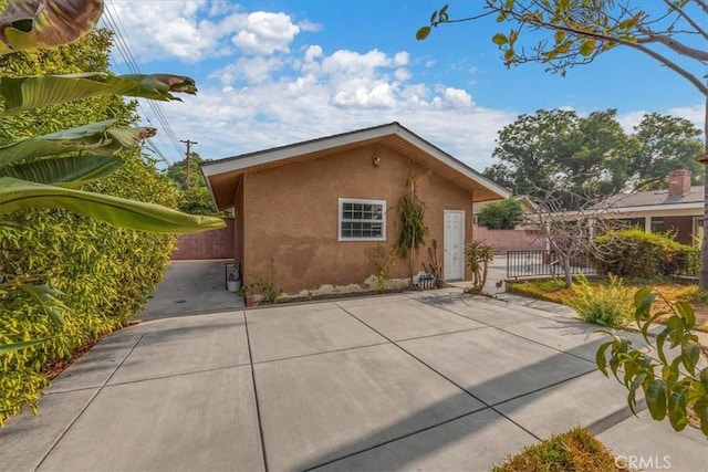 view of side of home with a patio area, fence, and stucco siding