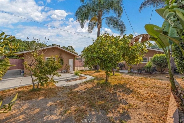 view of property hidden behind natural elements with fence and stucco siding