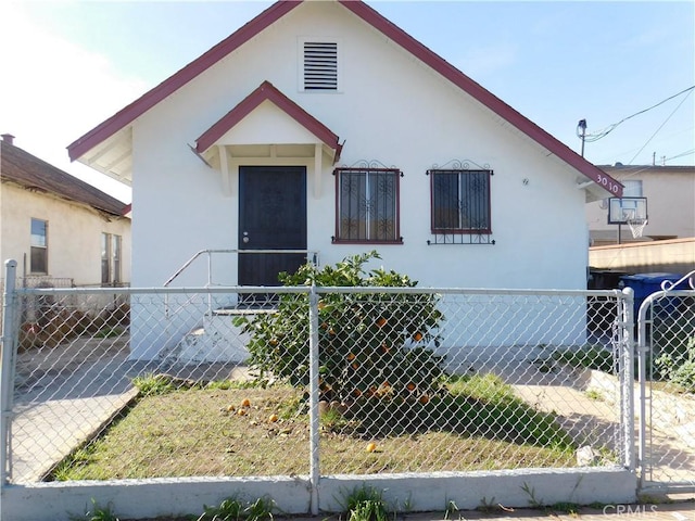 bungalow-style house featuring a fenced front yard, a gate, and stucco siding