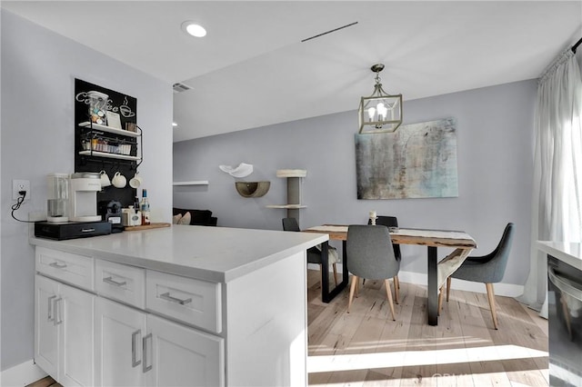 kitchen with light wood-type flooring, an inviting chandelier, white cabinets, light countertops, and dishwasher