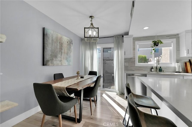 dining room featuring recessed lighting, light wood-style flooring, an inviting chandelier, and baseboards