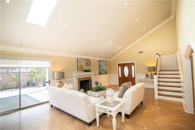 living room featuring a wainscoted wall, high vaulted ceiling, a fireplace, ornamental molding, and stairs