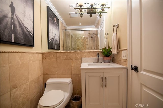 bathroom with vanity, a tile shower, crown molding, toilet, and tile walls