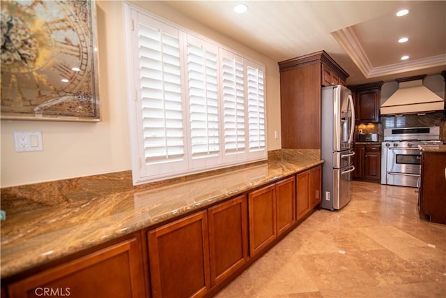 kitchen featuring ornamental molding, a tray ceiling, recessed lighting, appliances with stainless steel finishes, and custom exhaust hood