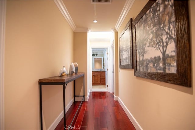 hallway featuring visible vents, baseboards, dark wood-type flooring, and ornamental molding