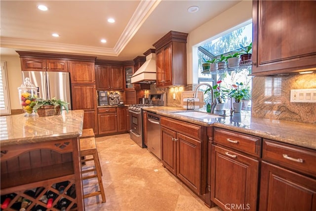 kitchen with light stone countertops, custom range hood, decorative backsplash, stainless steel appliances, and a sink