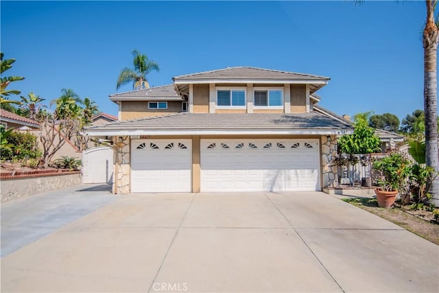 view of front of home featuring stucco siding, a tile roof, fence, concrete driveway, and a garage