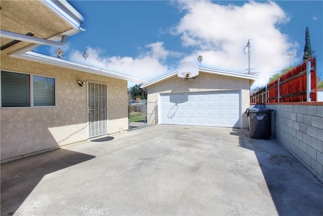 exterior space featuring a detached garage, fence, and an outbuilding