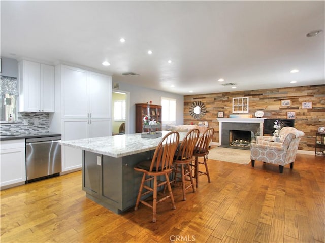 kitchen featuring white cabinetry, a fireplace, light wood-style flooring, and stainless steel dishwasher