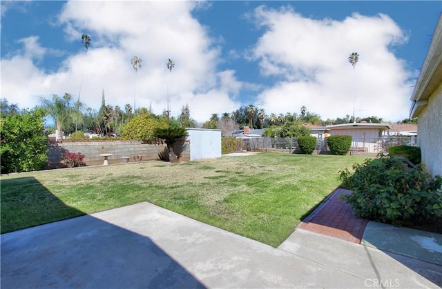 view of yard featuring a fenced backyard, an outdoor structure, and a patio