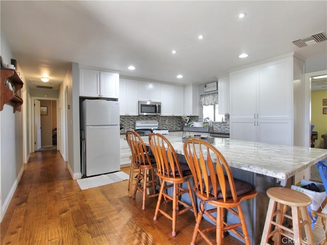 kitchen featuring white appliances, visible vents, white cabinets, and decorative backsplash