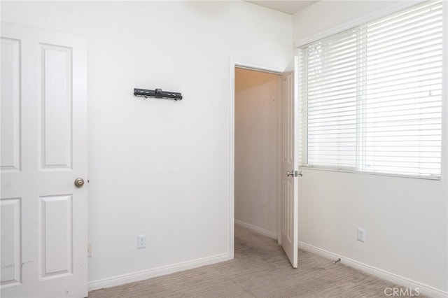 unfurnished bedroom featuring light carpet and baseboards