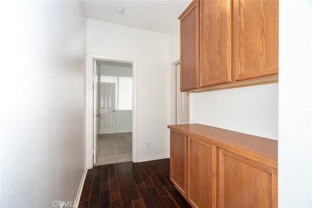 corridor with dark wood finished floors and baseboards