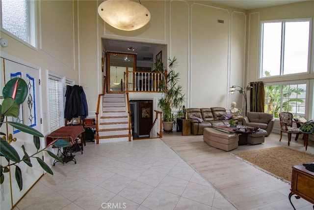 living area with stairway, a fireplace, a towering ceiling, and tile patterned floors