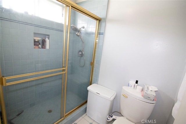 bathroom with toilet, a shower stall, and tile patterned flooring