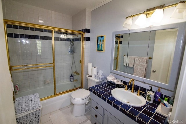 full bath featuring combined bath / shower with glass door, vanity, toilet, and tile patterned floors