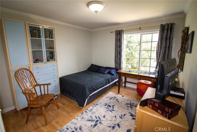 bedroom with crown molding and wood finished floors