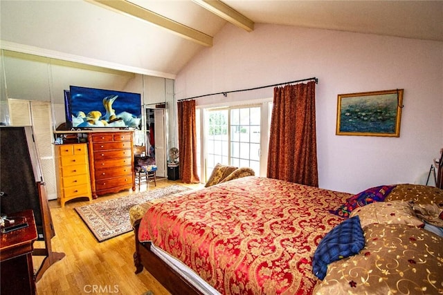 bedroom with lofted ceiling with beams and wood finished floors