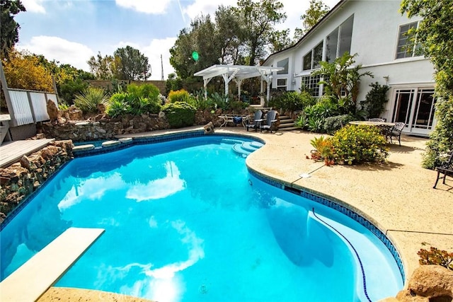 outdoor pool with a patio area and a diving board