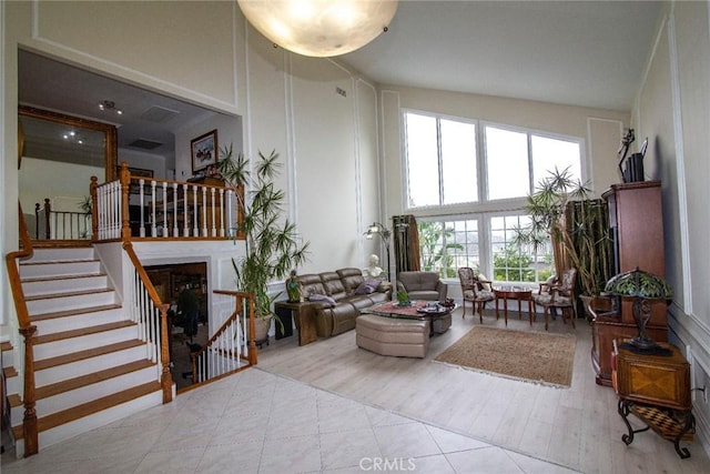 living area featuring a high ceiling, stairway, a fireplace, and wood finished floors