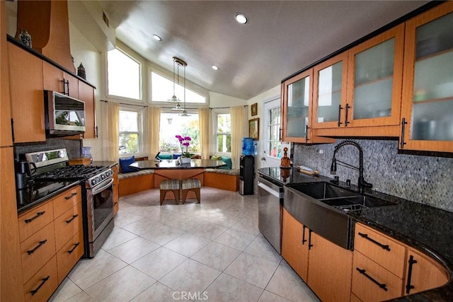 kitchen with light tile patterned floors, appliances with stainless steel finishes, glass insert cabinets, vaulted ceiling, and a sink