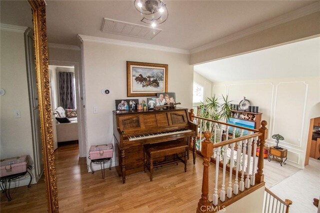 living area featuring light wood-type flooring, visible vents, and crown molding