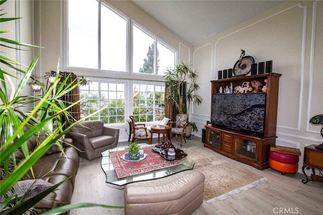 living room featuring a healthy amount of sunlight, wood finished floors, and a decorative wall