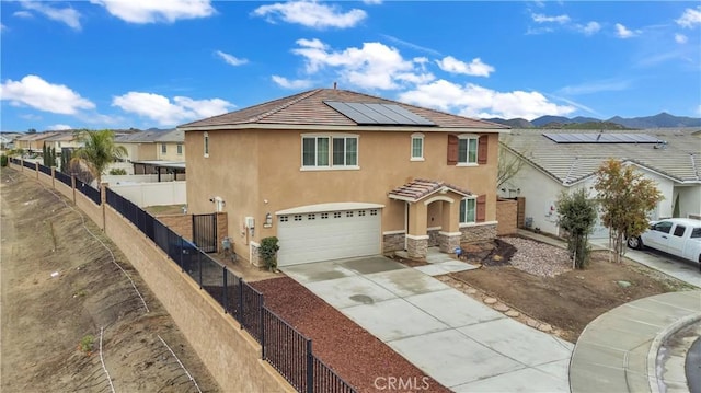 view of front of property featuring fence, driveway, solar panels, an attached garage, and stucco siding