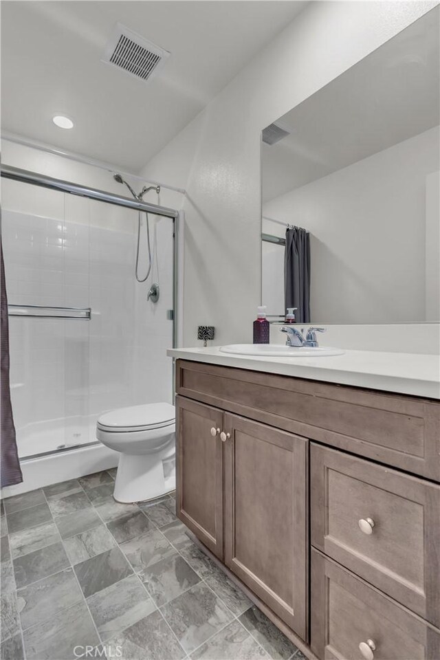 bathroom with vanity, toilet, visible vents, and a stall shower