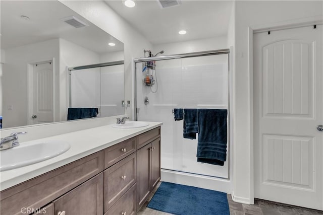 full bathroom featuring double vanity, visible vents, a stall shower, and a sink