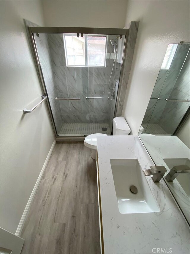 full bathroom with a stall shower, toilet, vanity, and wood finished floors