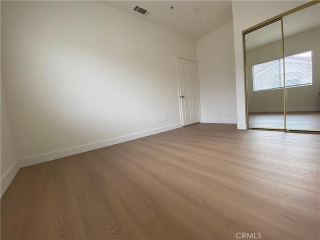 unfurnished bedroom with visible vents, baseboards, light wood-style floors, and a closet