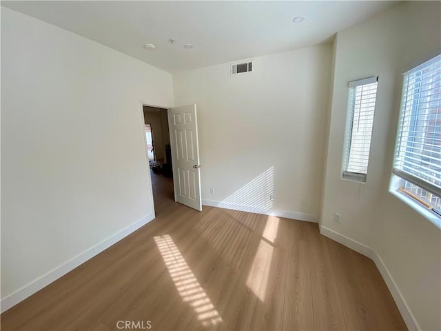 empty room with visible vents, light wood-style flooring, and baseboards