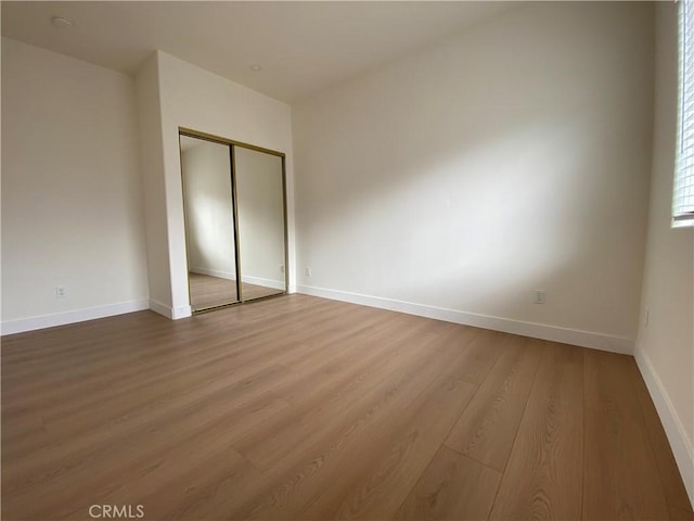 unfurnished bedroom with wood finished floors, a closet, and baseboards