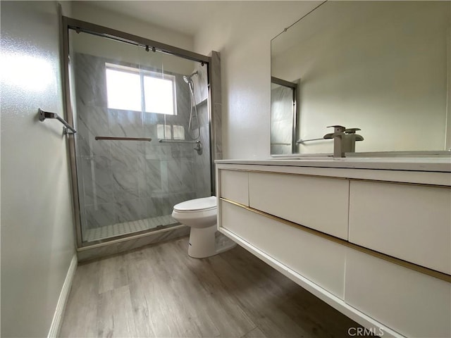 full bathroom with vanity, wood finished floors, baseboards, a shower stall, and toilet