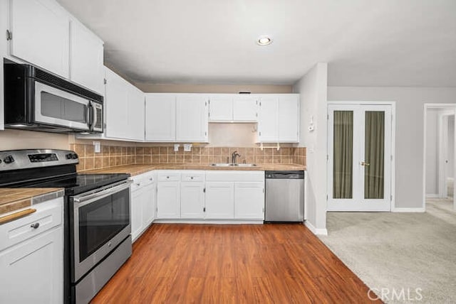 kitchen with a sink, backsplash, appliances with stainless steel finishes, and white cabinetry